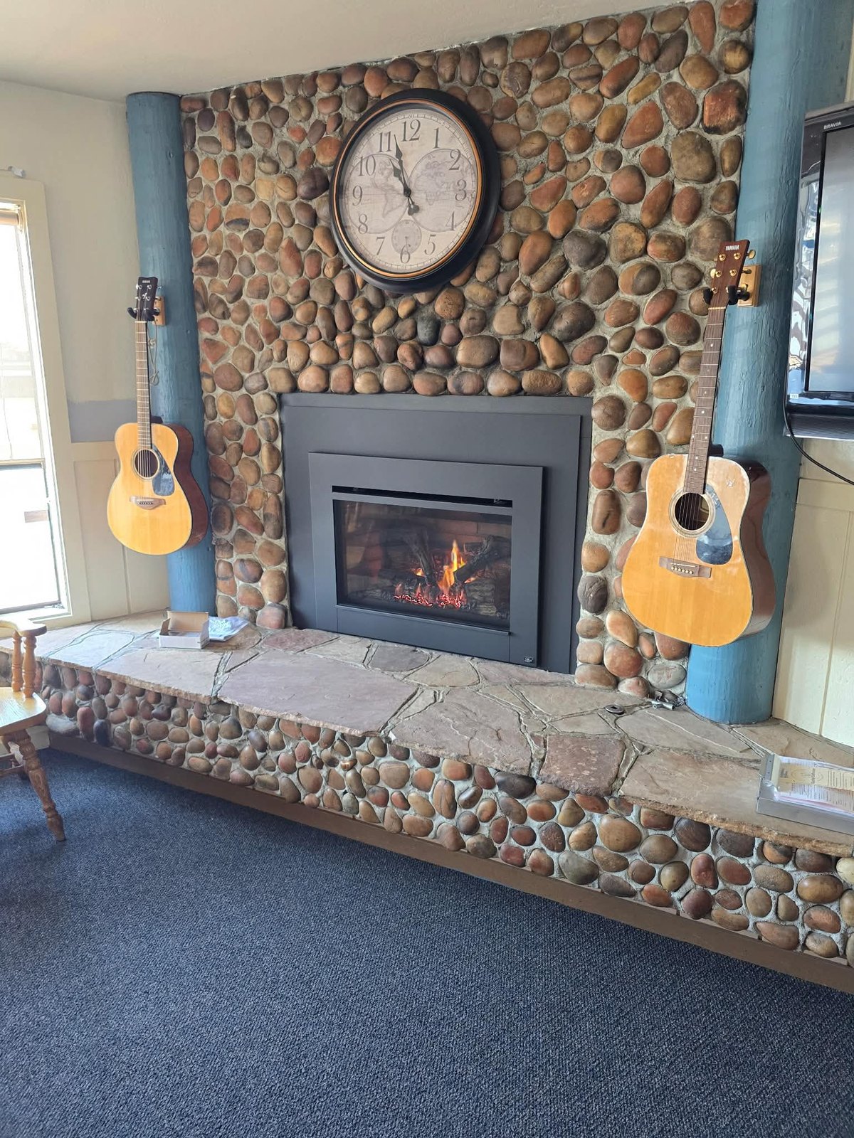 Gas insert in full river-rock stone wall with acoustic guitars — customer install